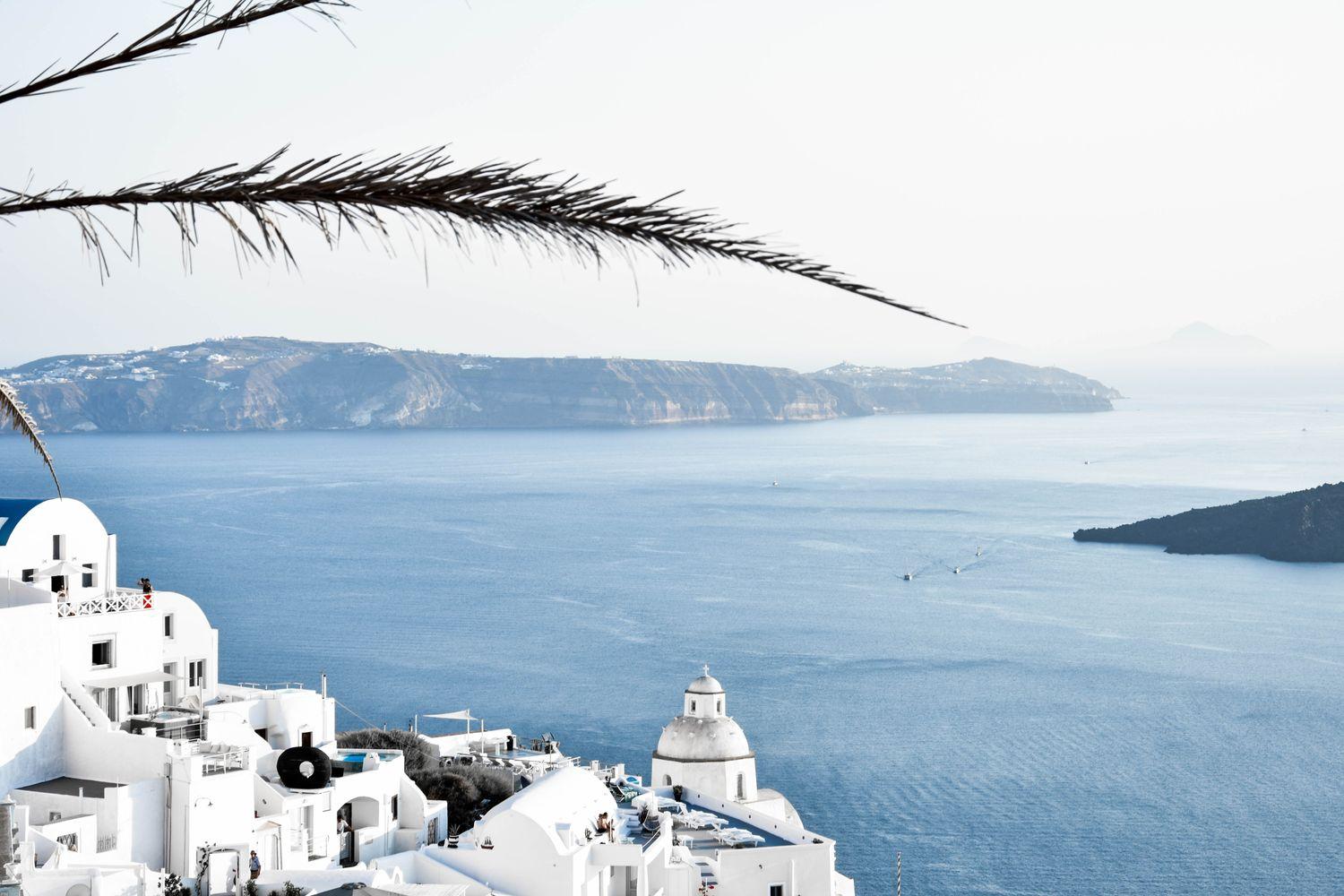 griechische Küstenstadt mit weißen Häusern vor blauem Meer mit einigen Landzungen