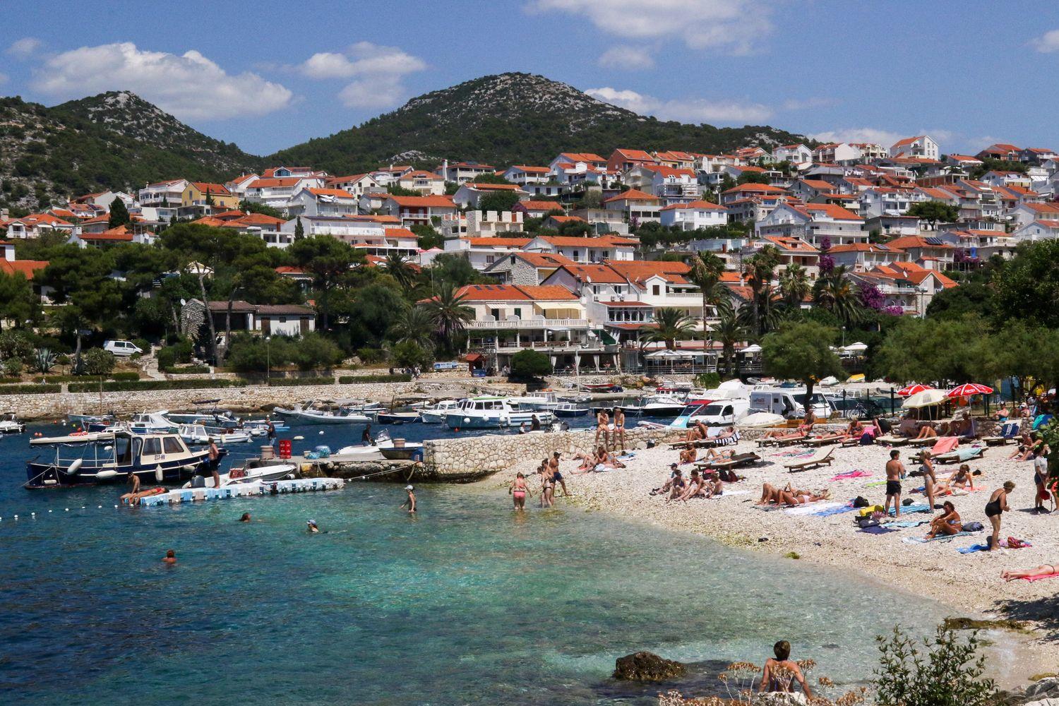 Altstadt und Touristenzentrum Hvar bei Mittagssonne, umgeben von blauem Meer und ankernden Yachten