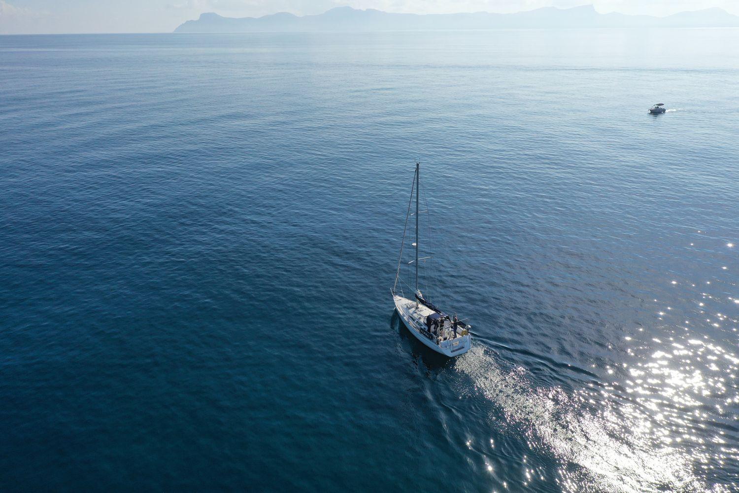 Blick von oben auf Segelyacht, umgeben von blauem Wasser bei sonnigem Wetter