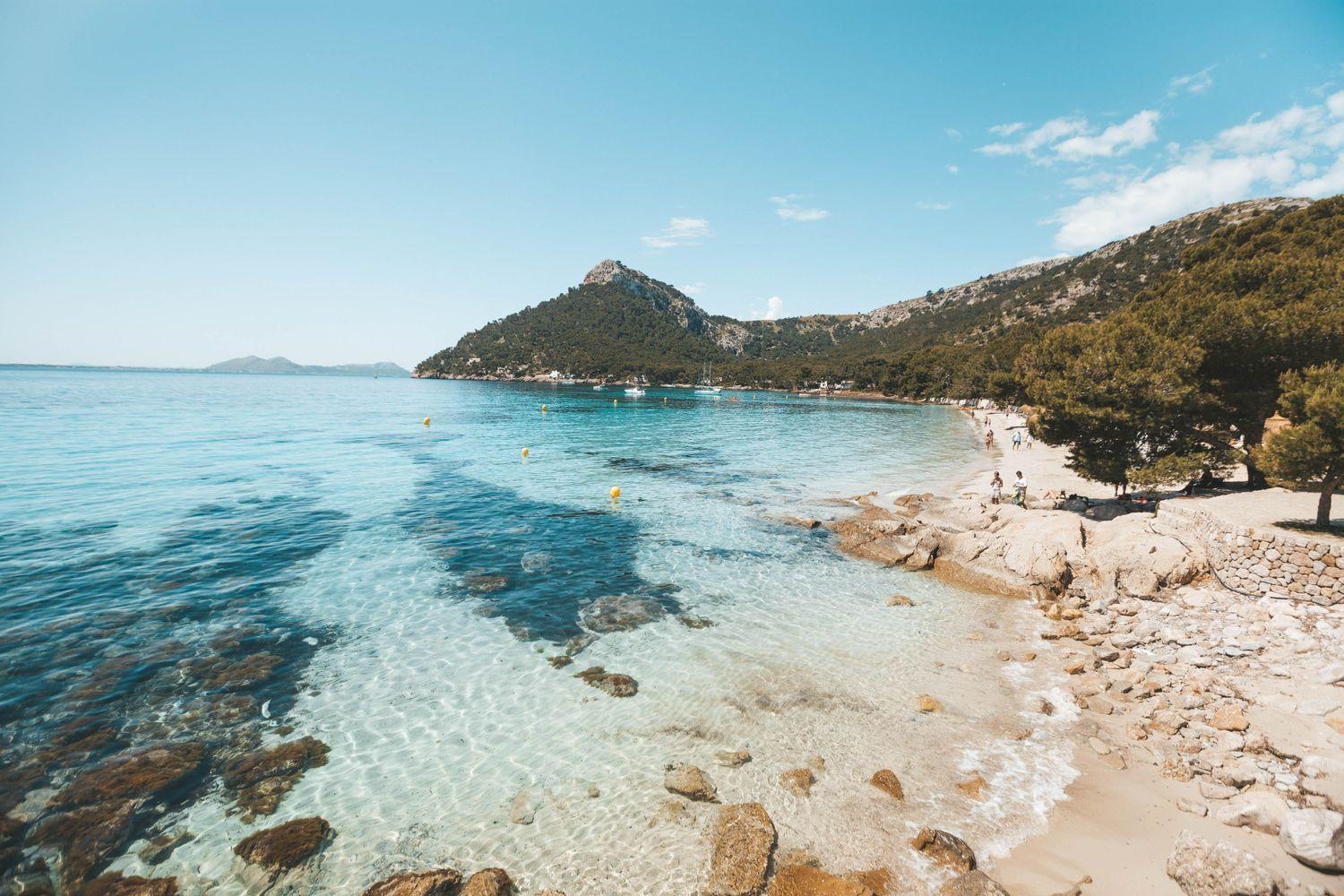 yachtcharter Mallorca mit weißem Sandstrand, klarem Wasser und Yachten in der Ferne 