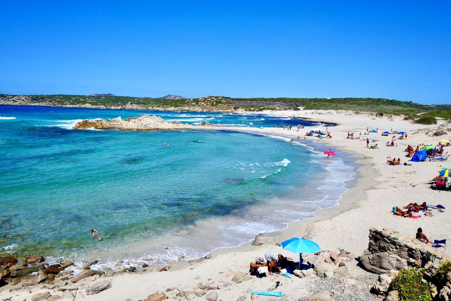 touristischer Sandstrand Nordsardiniens mit türkisem Wasser, bei sonnigem Wetter 